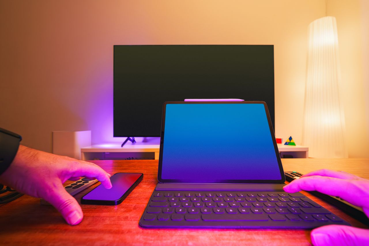 about-01 A vibrant workspace featuring a laptop, tablet, and TV with colorful lighting.